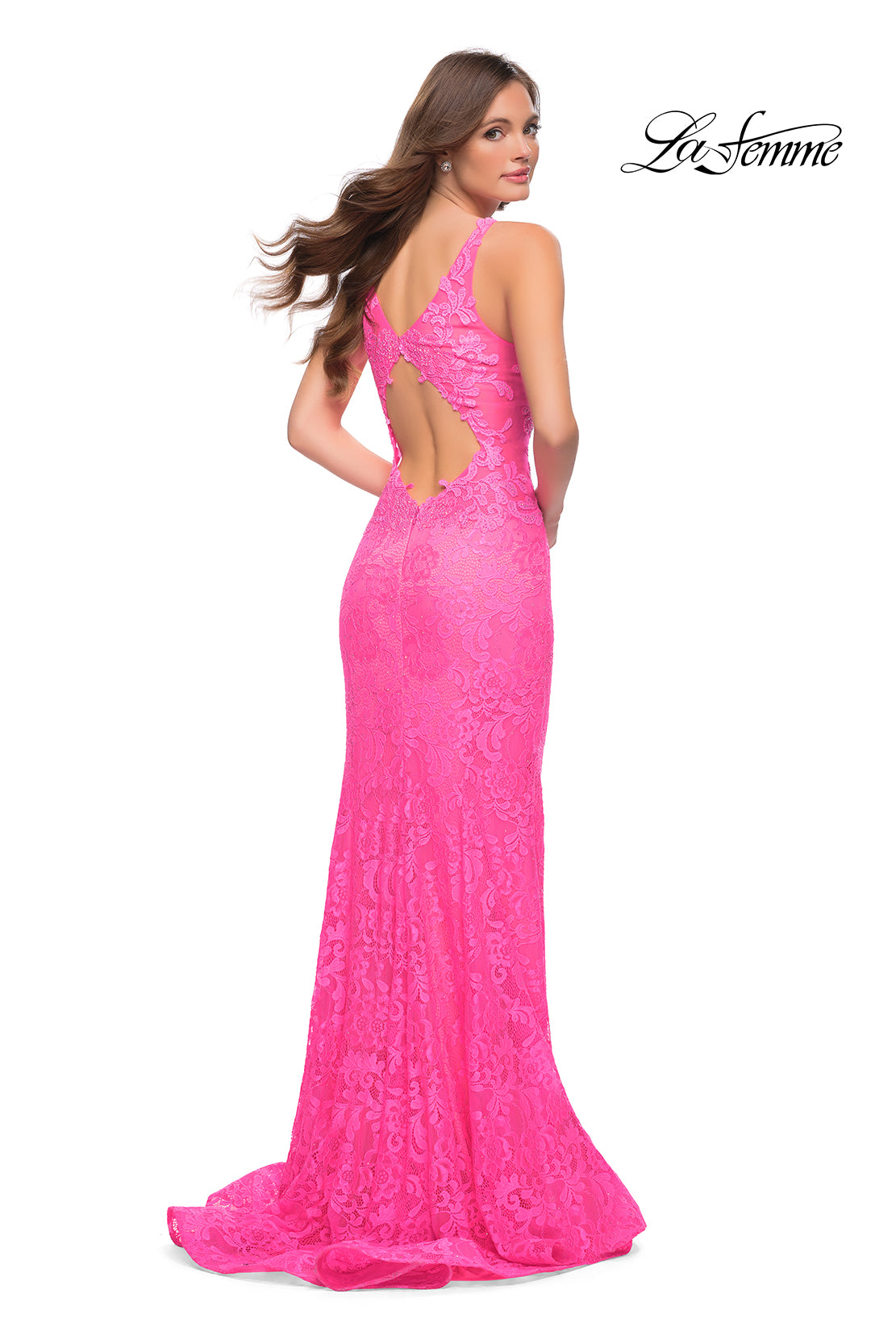 A woman stands, looking over her shoulder, wearing the Deep V-Neck Long Lace Prom Dress (La Femme 29978) in bright pink with lace details, open back, and mermaid silhouette. The La Femme logo appears in the top right corner.